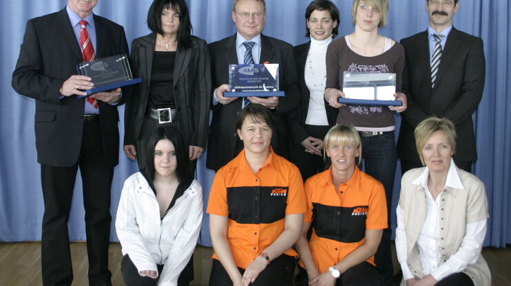 Gruppenfoto beim AMS Award Frauen in Technik, mit mehreren Teilnehmerinnen und Teilnehmern vor einer Bühne posierend.