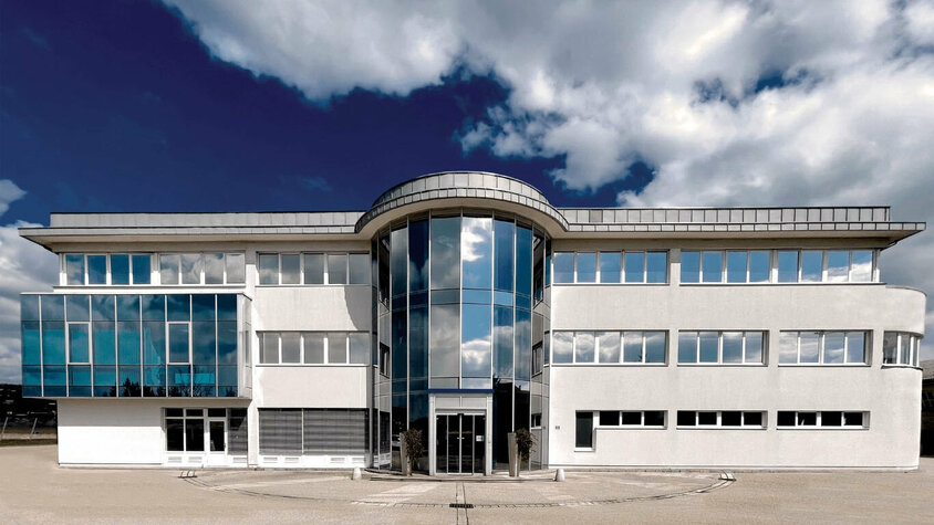 Außenaufnahme des Verwaltungstraktes der Entwicklungszentrale von weba in Dietach unter einem blauen Himmel mit Wolken.