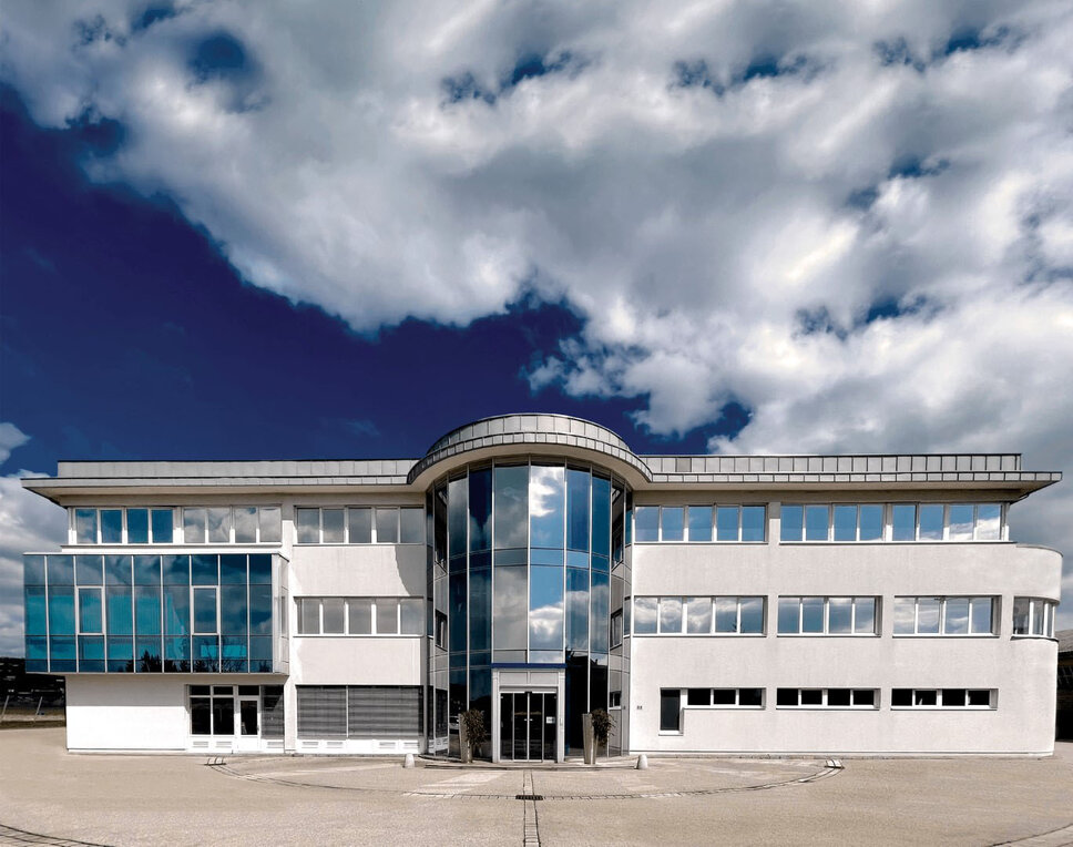 Außenaufnahme des Verwaltungstraktes der Entwicklungszentrale von weba in Dietach unter einem blauen Himmel mit Wolken.