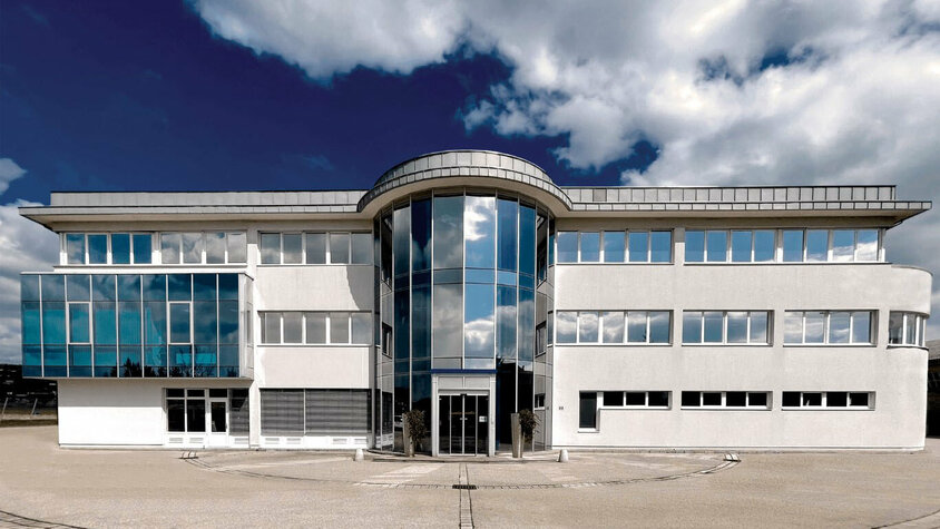 Außenaufnahme des Verwaltungstraktes der Entwicklungszentrale von weba in Dietach unter einem blauen Himmel mit Wolken.